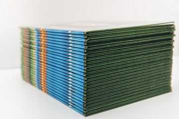 a lot of albums printed in color on a light background. a stack of green books, side view.