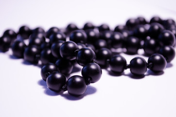 Shungite. Black beads on a white background. Photography for jewelry stores, fashion boys, style. Handwork. Matte black round mineral on a white background. Decoration of natural stones (necklace).