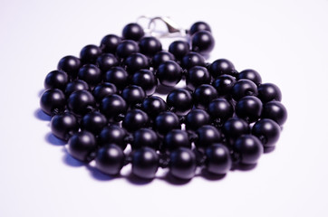 Shungite. Black beads on a white background. Photography for jewelry stores, fashion boys, style. Handwork. Matte black round mineral on a white background. Decoration of natural stones (necklace).
