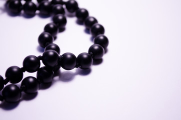 Shungite. Black beads on a white background. Photography for jewelry stores, fashion boys, style. Handwork. Matte black round mineral on a white background. Decoration of natural stones (necklace).