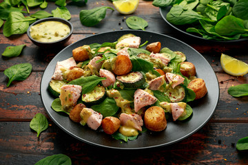 Salmon, new potato, courgette and spinach salad on wooden table