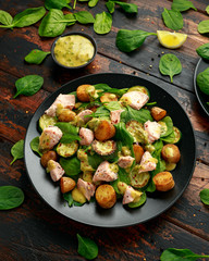 Salmon, new potato, courgette and spinach salad on wooden table