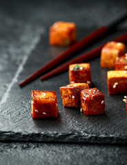 Fried Tofu with chopstick and sesame seeds on rustic stone board