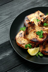 Homemade Grilled Pork loin chops in lemon sauce with herbs on rustic wooden table