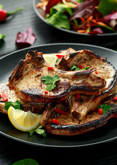 Homemade Grilled Pork loin chops in lemon sauce with herbs on rustic wooden table