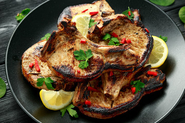Homemade Grilled Pork loin chops in lemon sauce with herbs on rustic wooden table
