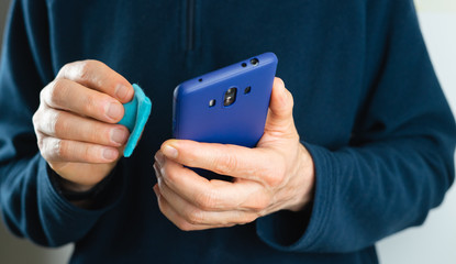 Man cleaning cell phone. Virus and disease prevention Covid-19. Contamination, germs, bacteria that are frequently touched.