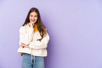 Young caucasian woman isolated on purple background smiling happy and confident, touching chin with hand.