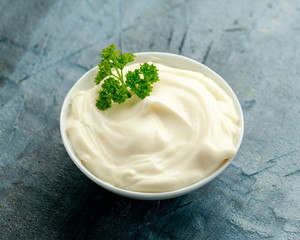 Mayonnaise sauce in a white bowl on old rustic table