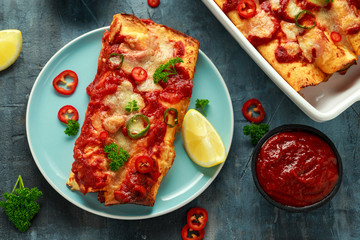 Baked Chicken fillets enchiladas with courgette, salsa sauce and cheese served with lemon wedges and chilies