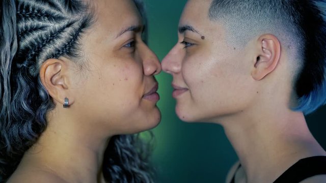Lesbian girlfriend kissing in love. Lgbt, gay pride, bisexual people. Punk lesbian woman with mohawk hairdo kissing and laughing with ethnic girlfriend with braids. Multicultural homosexual concept.