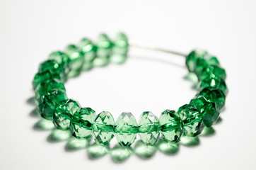Bracelet made from green faceted plastic beads. Crystals. Bracelet for a girl with a metal insert. Jewelry on a white background. Style and fashion. Close-up photo. Bijouterie. Bracelet close-up.