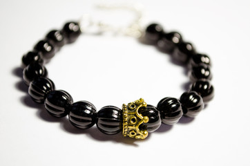 Bracelet made of black plastic beads with a crown-shaped decor. Unisex bracelet on a white background. Bead jewelry. Bijouterie. Macro photo.