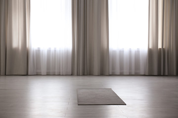 Grey yoga mat on floor in spacious room