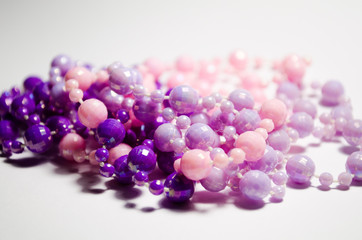 A scattering of delicate jewelry on the neck. Decorations of delicate violet, pink flowers and violet. Several necklaces on a white background. bijouterie for girls. The site of jewelry.