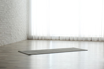 Unrolled grey yoga mat on floor in room