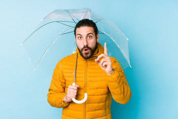 Young man wearing a long hair look holding an umbrella isolated having an idea, inspiration concept.