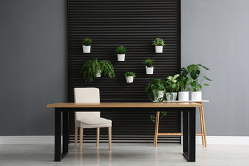Wooden table and plants in room. Stylish interior design
