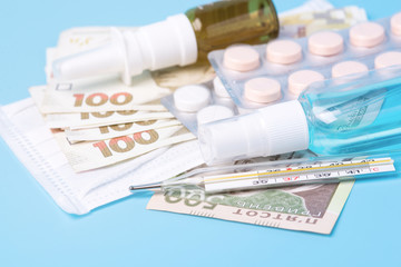 Hryvnia banknotes. Concept of expensive medecine. Reduce the risk of infection. The concept of protection against airborne diseases. Coronovirus and flu. Pills, spray, antiseptic on a blue background