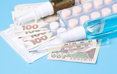 Hryvnia banknotes. Concept of expensive medecine. Reduce the risk of infection. The concept of protection against airborne diseases. Coronovirus and flu. Pills, spray, antiseptic on a blue background