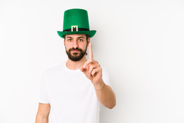 Young caucasian man wearing a saint patricks hat isolated showing number one with finger.
