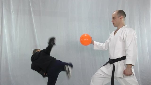A boy with a tracksuit hits the orange ball