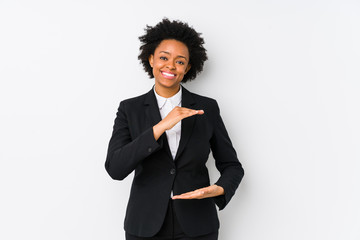 Middle aged african american business  woman against a white background isolated holding something with both hands, product presentation.