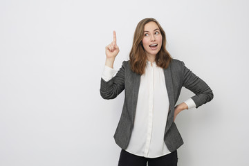 Businesswoman is pointing up while looking like she got an great idea 