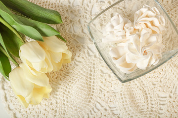 Good morning concept, french meringues in a vase and yellow tulips on a white napkin. Vintage or retro background, top view, copy space.