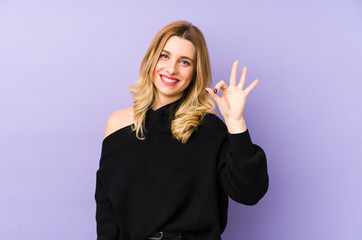 Young blonde woman isolated cheerful and confident showing ok gesture.