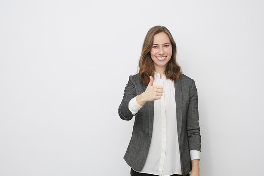 Businesswoman is pointing the thumb up while looking proud