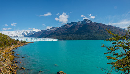 Panoramic view of the huge Perito Moreno glacier in Patagonia in golden Autumn, South America, sunny day, blue sky
