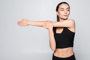 Fototapeta na wymiar Portrait of a smiling fitness woman stretching her hands over white background