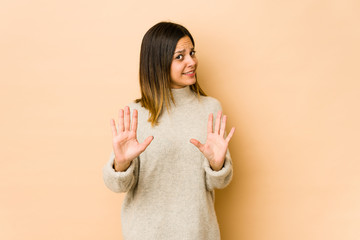 Young woman isolated on beige background rejecting someone showing a gesture of disgust.