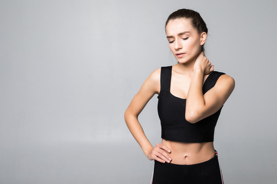 Portrait of a woman in a fitness outfit experiencing neck, shoulder and back pain isolated on white background