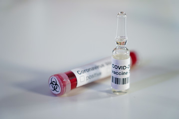 Close up of positive Coronavirus blood test with biohazard label and ampoule with COVID-2019...