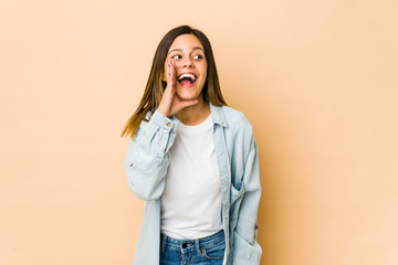 Young woman isolated on beige background shouting excited to front.