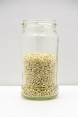 Glass jar with barley on a white background, side view.