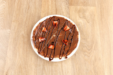 Chocolate cake with strawberry on a white plate on a texture background