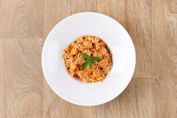 Fusilli with Shrimp pasta with basil leaves and Parmesan cheese in a white plate on a wooden background