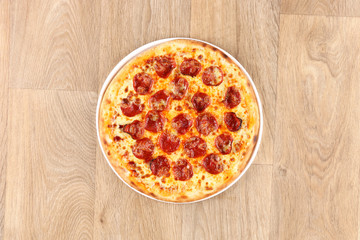 Pepperoni pizza with vegetables on a wooden background