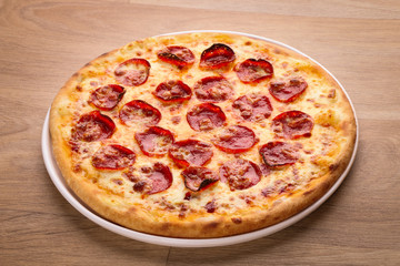 Pepperoni pizza with vegetables on a wooden background