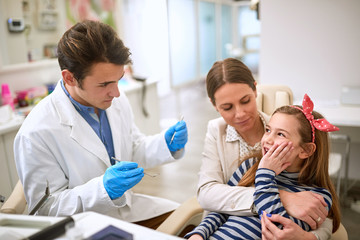 Obraz premium Dentist checking up girl with tooth problem