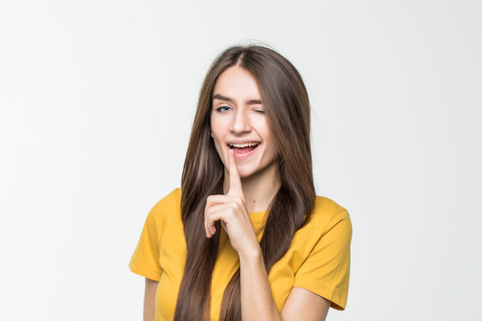 Portrait of young woman keeping finger on her lips and asking to keep quiet isolated over white background