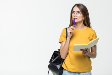 Portrait of a smiling casual girl student with backpack writing in a notepad while standing with...