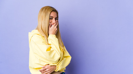 Fototapeta premium Young blonde woman isolated on purple background laughing happy, carefree, natural emotion.
