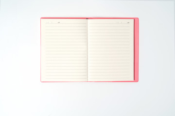 Pink notebook on white desk. Business minimal concept for women. Flat lay, top view, copy space
