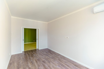 Fototapeta na wymiar An empty room with white walls and wooden floors . Fresh new renovation. The door to the corridor.