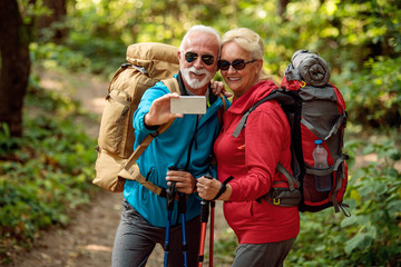 Happy senior couple of hikers in the forest.