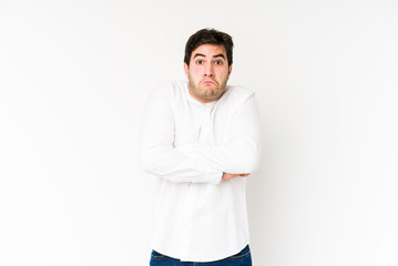 Young man isolated on white background shrugs shoulders and open eyes confused.